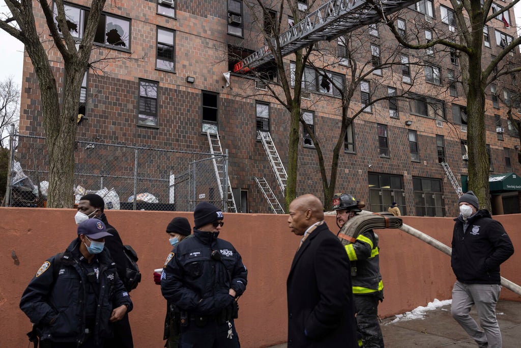 New York City Mayor Eric Adams, 3rd right, walks by an apartment building where a deadly fire occurred in the Bronx on Sunday, Jan. 9, 2022, in New York. (AP Photo/Yuki Iwamura)