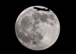 An aircraft passes the full moon over Frankfurt, Germany, Sunday, May 15, 2022. (AP Photo/Michael Probst)