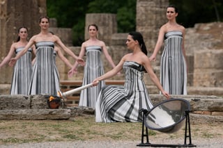 Actress Mary Mina, playing high priestess, lights a torch during the official ceremony of the flame lighting for the Paris Olympics, at the Ancient Olympia site, Greece, Tuesday, April 16, 2024. The flame will be carried through Greece for 11 days before being handed over to Paris organizers on April 26. (AP Photo/Thanassis Stavrakis)