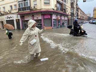 MA06. MÁLAGA, 13/11/2024.- Una mujer hace fotos con el agua hasta las rodillas en Málaga donde las fuertes trombas de agua y granizo que se registran este miércoles han causado inundaciones y la acumulación de grandes balsas en algunas de las principales avenidas de todos los distritos de la ciudad.EFE/María Alonso
