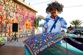 El marakame Julián Carrillo observa el paisaje de Torreón desde lo alto del cerro de las Noas. En sus ropas de lana sobresalen bordados azules hechos a mano, mientras el viento agita las plumas de su sombrero y también hace sonar las semillas que cuelgan del ala. Originario de San Andrés Cohamiata, una comunidad ubicada en el municipio jalisciense de Mezquitic, Carrillo lidera a un grupo de 18 artesanos wixárikas que llegaron a Torreón para trabajar en la escultura monumental del Centro Ceremonial Kauyumari, proyecto que tendrá la forma de una venada azul y es impulsado por la artista lagunera Leyla Brashka.

Mientras cae la tarde, otros dos jóvenes wixárikas, José y Benita, dan una demostración de su trabajo en el tercer nivel de Puerto Noas. Con cuidado y precisión, colocan cuentas de chaquira sobre la superficie de una pieza metálica; crean cosmovisiones, mosaicos llenos de colores y de símbolos huicholes como el peyote (híkuri) o el venado azul (kauyumari). Se trata de un saber antiguo, una herencia que pasa de generación en generación. Todos en San Andrés Cohamiata son artesanos, asegura el marakame Julián Carrillo