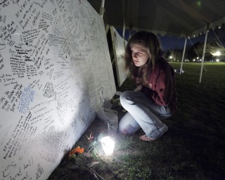 Estudiantes de la Universidad Tecnológica de Virginia rindieron tributo a los estudiantes asesinados el lunes escribiendo mensajes sobre tablones en el campo de la escuela. (AP)