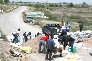 Trabajadores del municipio de Lerdo colocan costales con arena en la carretera a Villa Juárez, a la altura de la colonia El Centauro, en prevención de la avenida del río Nazas.
