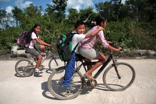 A la escuela. Niños se dirigen en bicicleta a su escuela en uno de los suburbios pobres de Cancún.  ARCHIVO