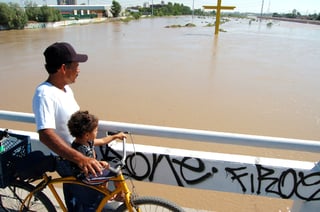 Corre el río. Un hombre se detiene con su hijo a observar el paso del Nazas sobre uno de los puentes.  EL SIGLO DE TORREÓN / SERGIO REYES