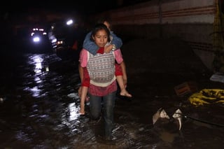 Fuertes lluvias. En la imagen se observa a una niña cargando a su hermana, tras las fuertes lluvias en una comunidad Puebla.