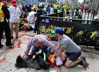 Ataque. En el pánico tras las explosiones, algunos corredores atendieron a los heridos en la meta del Maratón de Boston. 