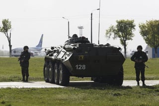 Lucha.  Soldados ucranianos armados hacen guardia junto a un vehículo blindado en el aeropuerto Boryspil de Kiev, Ucrania.