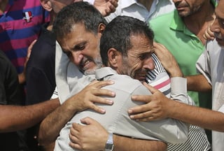 Parientes de siete miembros de una misma familia se abrazan durante el funeral por sus familiares en Beit Lahiya. (EFE)