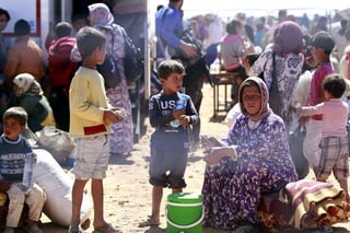 Riesgos. Una familia de refugiados sirios espera en la frontera para tener autorización de pasar a Turquía en medio de una gran tensión pues el EI amenazó con matar a civiles. (EFE)
