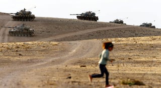 Dimensiones. Una pequeña corre mientras tanques turcos patrullan la frontera con Siria.