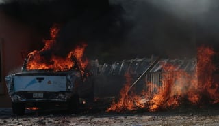 Fuego. La camioneta oficial arde y la puerte eléctrica yace también quemándose tras los ataques.
