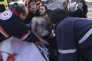 Auxilian. Paramédicos dan auxilio a uno de los apuñalados en el autobús en la ciudad de Tel Aviv. (EFE)