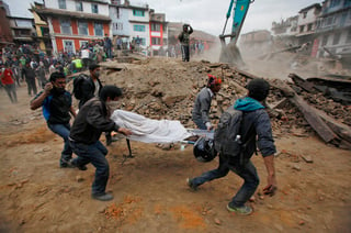 Tragedia. Un grupo de jóvenes carga un cadáver mientras maquinaria pesada junta los escombros  en busca de más cuerpos. (AP)