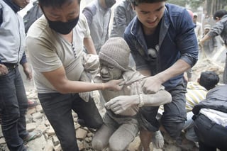Destrucción. Dos hombres rescatan de los escombros a una persona luego del fuerte sismo que sacudió ayer la capital de Nepal.