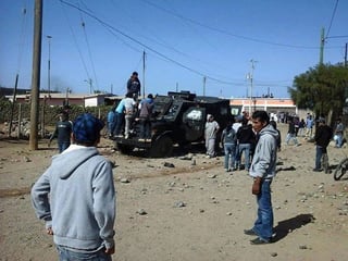 En San Quintín.  Un grupo de personas destruye un auto de la policía  durante un enfrentamiento.