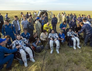 Tras caer a tierra, los tres astronautas fueron sacados de la cápsula y ayudados a sentarse sobre la hierba de la estepa, donde posaron sonrientes ante los fotógrafos tras retirarse las escafandras. (EFE)