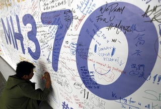 Mensaje. Un hombre escribiendo mensajes en honor a las víctimas del vuelo MH370.