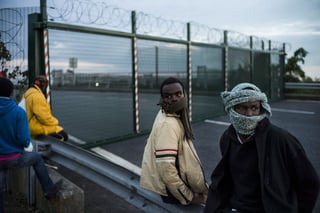 Salto. Migrantes esperan saltar una cerca para tomar un tren en su ruta hacia Inglaterra, en Calais (Francia).