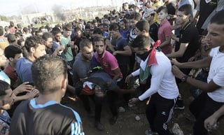 Herido.  Jóvenes palestinos ayudan a uno de sus compañeros heridos durante un enfrentamiento con el Ejército israelí. (EFE)