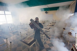 Acciones. Un brigadista en Colombia fumiga un salón de clases; Colombia y Brasil son las regiones más afectadas por el zika.