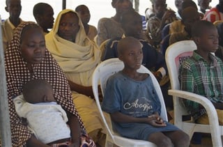 Niños y mujeres sentados esperando su liberación. (AP)