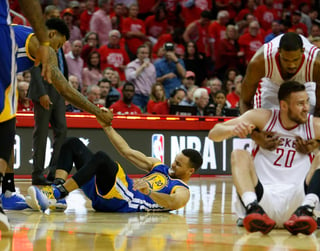 Stephen Curry es ayudado a levantarse tras resbalar en la duela durante el cuarto partido de la serie ante los Rockets de Houston. Curry estará fuera al menos dos semanas por un esguince en la rodilla derecha. (AP)