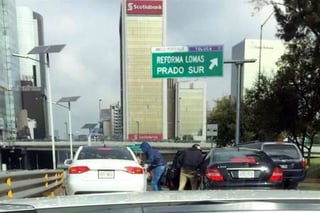 En la fotografía se observa a dos sujetos con chamarra y gorra cuando abren e intentar abrir dos automóviles de lujo, parados por el tránsito de la zona de Polanco y Lomas. (TWITTER)