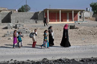 Protegidas. Una mujer y varias niñas caminan en las calles de Qayyarah con una bandera blanca.