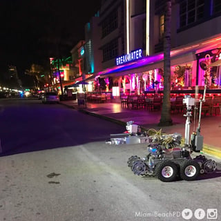 Una fotografía en la que se ve en primer plano lo que parece un robot para desactivar explosivos en medio de un Ocean Drive sin gente acompaña el mensaje policial. (TWITTER)
