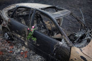 Luto. Colocaron unas rosas en un auto en donde se encontró a una de las víctimas que murió por el fuego. 