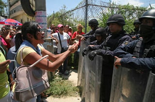 Preocupación.  Familiares de internos se enfrentan a la Policía Estatal que resguarda el perímetro de la prisión estatal de Acapulco,  Guerrero, en donde estalló una riña entre bandas rivales, con un saldo de 28 muertos. (AP)