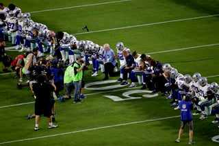Todo el plantel de Dallas se arrodilló junto al dueño Jerry Jones y su familia ayer, antes que se desplegara una gigantesca bandera de Estados Unidos. (AP)