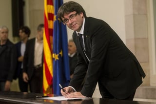 Documento. Carles Puigdemont firma el documento sobre la Independencia después de comparecer ante el pleno del Parlamento. (EFE)