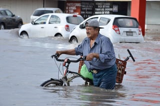 Con el agua a la cintura. Una fuerte tormenta azotó la tarde de ayer la zona metropolitana de La Laguna y dejó graves inundaciones. En la imagen, un ciclista intenta avanzar en medio del agua en el bulevar Diagonal Las Fuentes, en Torreón. (EL SIGLO DE TORREÓN/FERNANDO COMPEÁN)