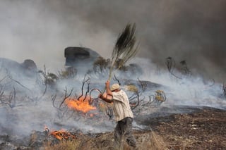 Un hombre trata de sofocar las llamas en Almeidinha. (AP)
