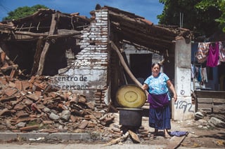 Una habitante cocina junto a una vivienda destruida marcada con los folios que le permitiran acceder a los apoyos del gobierno para reconstruir su vivienda, en el estado de Oaxaca. Foto: EFE/Luis Villalobos