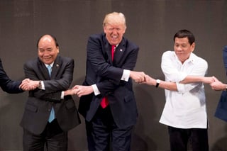 Su papel. Trump reacciona al ‘apretón de manos del ASEAN’ con los mandatario Tran Dai Quang (Izq.) y Rodrigo Duterte. (AP)
