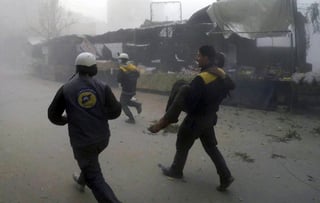 Apoyo. Cascos Blancos trasladan a un herido después de los ataques aéreos contra un suburbio en poder de los rebeldes. (AP)