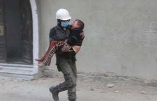 Salvarlo. Un miembro de los Cascos Blancos carga a un niño luego de uno de los bombardeos que golpeó nuevamente a Guta Oriental. (AP y EFE)