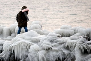 Muelle. Una mujer camina en el muelle cubierto de hielo sobre la orilla del lago en Ginebra, Suiza. (AP/EFE)