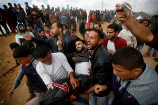 Conflicto abierto. Manifestantes palestinos auxilian a un joven herido durante el choque con fuerzas armadas israelíes en Gaza.