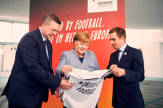 La canciller alemana Angela Merkel, al centro; el director de la Federación Alemana de Futbol, Reinhard Grindel, izquierda, y el exjugador Philipp Lahm, derecha, promueven que Alemania sea sede de la Eurocopa de 2024. Alemania desea unir al continente