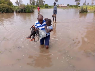 Crece. El reportero Stevo Letoo ayuda a un menor a cruzar la inundación en la aldea Kakola Ombaka. (TWITTER/@citizentvkenya)