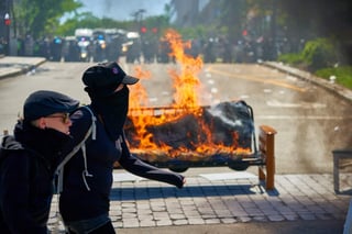 Varios policías observan un sofá en llamas durante una protesta en el marco del G7 en Quebec, Canadá. (AGENCIAS)
