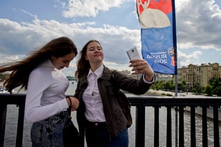 Dos mujeres se toman fotos desde el puente Krymsky de Moscú, adornado con pendones del Mundial. (AP)