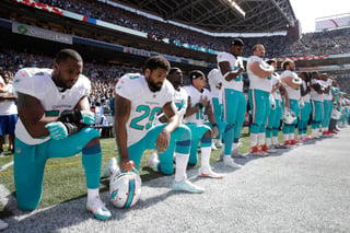 En esta fotografía del 11 de septiembre de 2017, varios jugadores de los Dolphins de Miami se hincan en protesta durante la ejecución del himno nacional estadounidense antes del partido contra los Seahawks de Seattle. (AP)