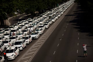 Unhombre toma una fotografía de taxis estacionados bloqueando la avenida principal de Castellana en Madrid, España. (AP)