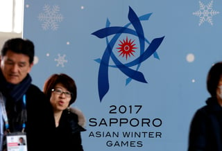 Personas caminan frente a un cartel de los Juegos Asiáticos de Invierno de Sapporo 2017, exhibido en el principal centro para medios en Sapporo, en la isla japonesa de Hokkaido.