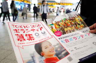 Panfletos para reclutar voluntarios para los Juegos Olímpicos y Paralímpicos de 2020 son repartidos en una estación de trenes en Tokio.